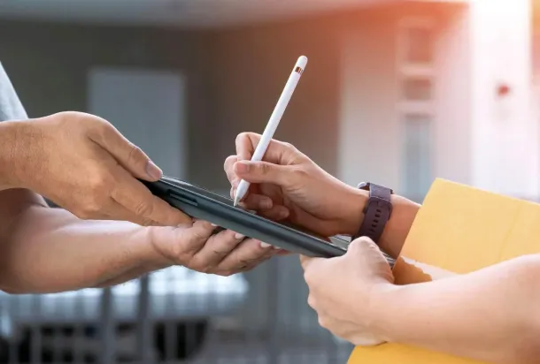 A delivery man giving a box to someone and asking for a signature